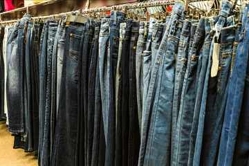 Row of denim pants hanging on trempels. Jeans in clothing store.