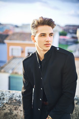 Wall Mural - Portrait of handsome young man in black posing on the street