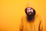 Fototapeta  - Cool bearded hipster looking at the camera with angry face over yellow background