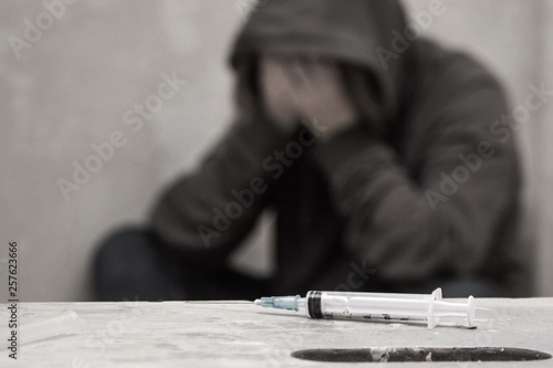 Cuadros en Lienzo Syringe with out of focus man drug addict sitting in the background