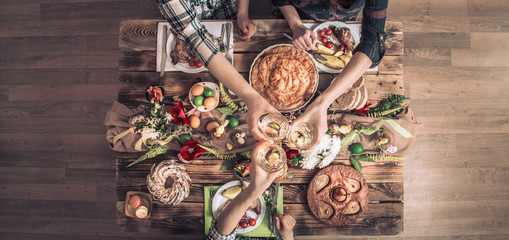 Holiday friends or family at the festive table with rabbit meat, vegetables, pies, eggs, top view.