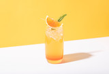 Cold and refreshing orange punch cocktail with orange slice on yellow background. summer drink.