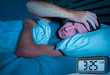 © TheVisualsYouNeed - desperate man in stress sleepless on bed with eyes wide opened suffering insomnia sleeping disorder depressed with digital alarm clock