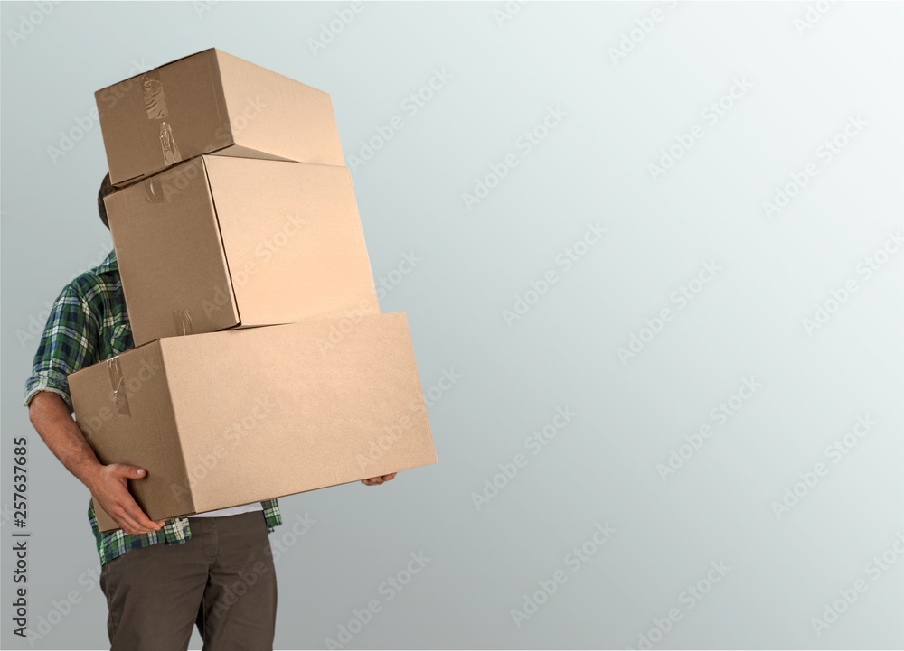 Delivery man carrying stacked boxes in front of face against  background - obrazy, fototapety, plakaty 