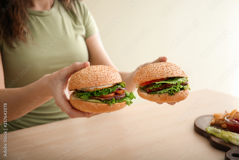 Woman with tasty fresh burgers at table