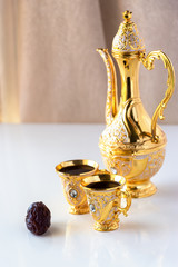 Wall Mural - Still life with traditional golden arabic coffee set with dallah and cup. White background. Ramadan concept.