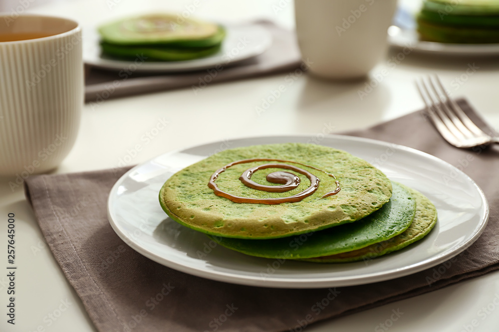Tasty green pancakes served for breakfast on table