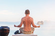 © Eskymaks - Young Man Meditating overlooking ocean.