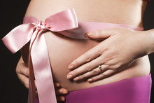 Pregnant Belly With Pink Ribbon Isolated On Dark Background