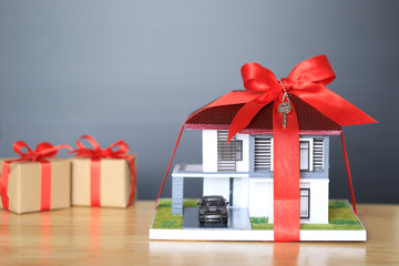 Real estate and Gift new home concept,Model house with Red ribbon and key on black background