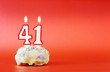 Forty one years birthday. Cupcake with white burning candle in the form of number 41. Vivid red background with copy space