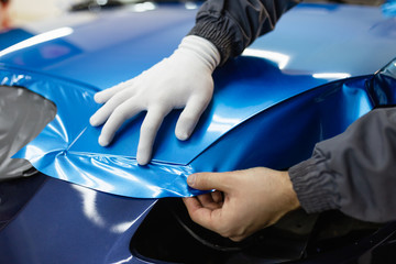 Wall Mural - Car wrapping specialist putting vinyl foil or film on car. Selective focus.