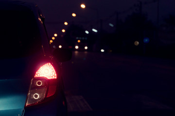 Focus the rear brake lights of the car on the night road in Thailand.