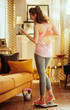 © Alliance - woman standing at smart scale and rejoicing after weight result