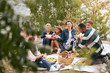 © Maskot - Happy family and friends having food on lakeshore in park
