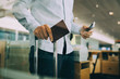 © Maskot - Midsection of businessman holding passport and smart phone at airport