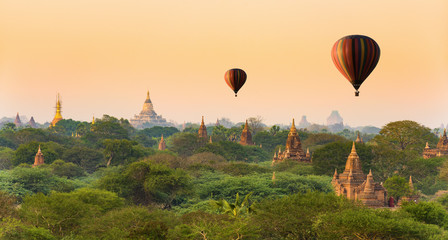 Stunning view of the beautiful Bagan ancient city (formerly Pagan) during sunset with two hot air balloons flying over the temples. The Bagan Archaeological Zone is a main attraction in Myanmar.