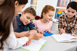 © LIGHTFIELD STUDIOS - Four pupils with notebook and books at desk in classroom