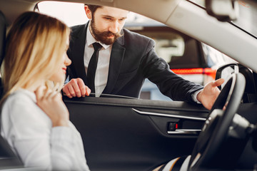 Woman buying the car. Lady in a car salon. Manager with a client