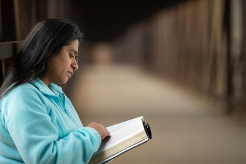Wall Mural - Hispanic Woman Reading Bible On Bridge