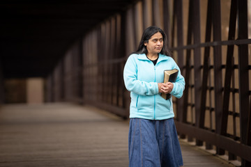 Wall Mural - Hispanic Woman Holding Bible On a Bridge
