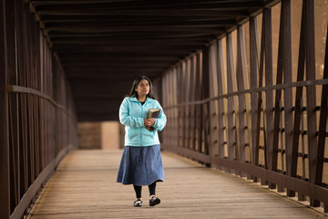 Wall Mural - Hispanic Woman Walking Down A Bridge With Her Bible
