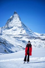 Wall Mural - Young woman tourists in the snow with the Matterhorn Mountain background, Zermatt, Switzerland.