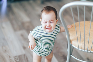Poster - Crying little cutie drk-haired girl, stands crying loudly, standing near chair at home