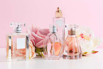 Bottle of perfume with flowers on color background