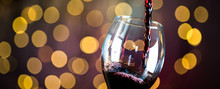  Pouring Red Wine Into The Glass. Golden Bokeh Background.