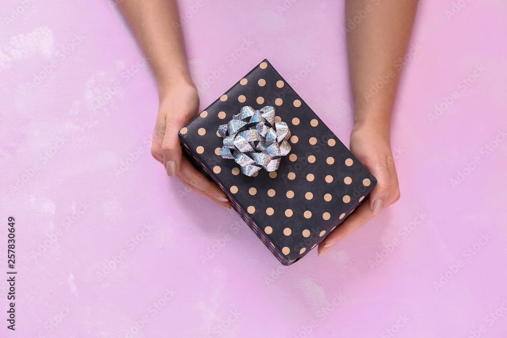 Female hands with gift box on color background