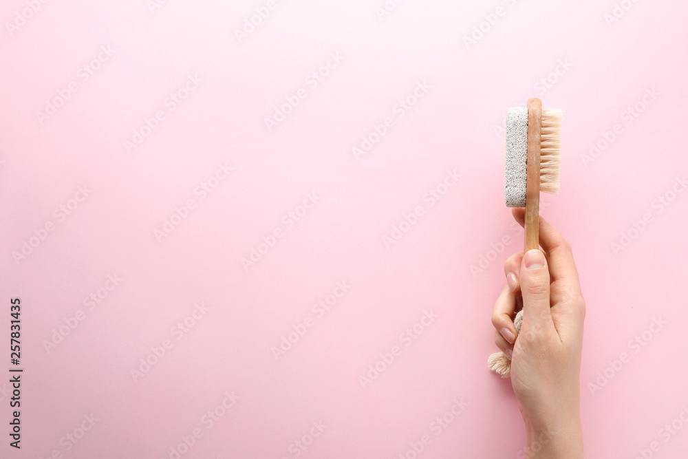 Female hand with massage brush on color background