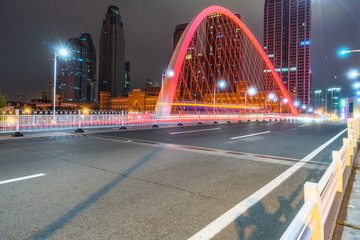 Wall Mural - car light trails on steel bridge with city skyline.