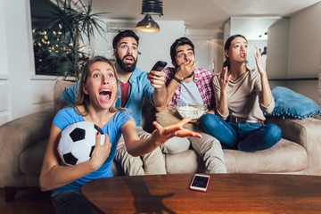 Happy friends or football fans watching soccer on tv and celebrating victory at home.Friendship, sports and entertainment concept.