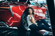 © LIGHTFIELD STUDIOS - selective focus of happy woman sitting on floor near new luxurious car