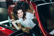 © LIGHTFIELD STUDIOS - selective focus of smiling pretty woman sitting in new red car