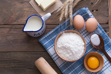 Cooking and baking concept. Baking ingredients on wooden  table. Eggs, butter, flour and tablecloth. Home baking, homemade cooking flat lay top view