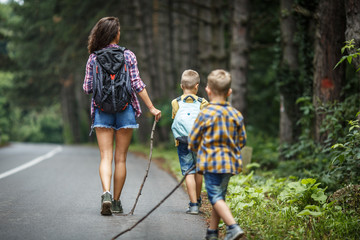 Wall Mural - mother and her little sons hiking by the rural country road.outdoor spring leisure concept.