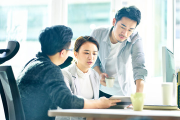 three young asian entrepreneurs discussing business in office