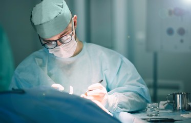 work of the surgeon in the hospital operating room. concentrated doctor with glasses.