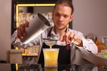 Wall Mural - Whiskey Sour alcohol cocktail with orange slice and ice cubes on black mirror background made by man bartender