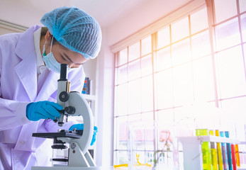 Young Asia  woman scientist working in laboratory.She is looking microscope.She is trying and research with red and blue test tube. Experiment , chemical Photo concept develop and medicine.