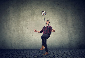 Full length of a young guy juggling a football