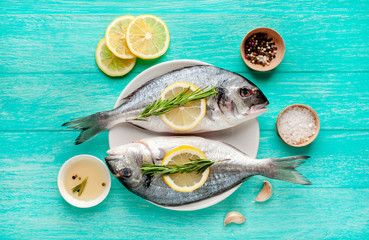 Dorado fish in a plate with spices and olive oil on a wooden table