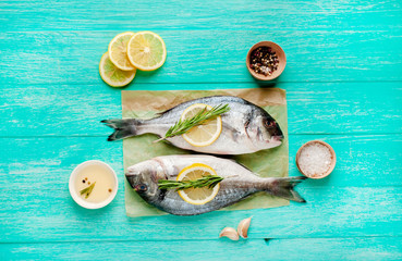 Two fresh raw Dorado fish with spices and olive oil on a wooden