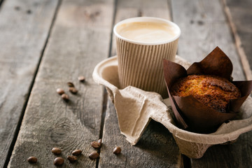 Coffee to go with muffin on wood background, copy space