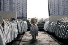 Creepy Doll With Yellow Hair Stands Between The Beds