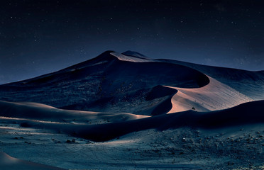 desert of namib at night with orange sand dunes and starry sky