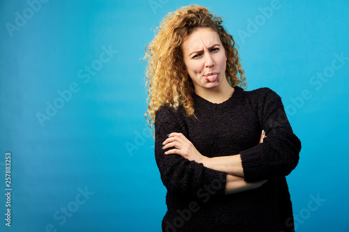 Fotografía Attractive young redhead curly woman showing her tongue with disgust