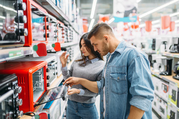 couple buys an electric oven in a supermarket